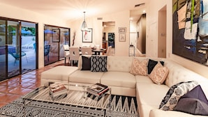 A modern living room with a sofa, coffee table, and a dining area with chairs. - Andiamo al Sole (Palm Springs)