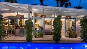 Ein modernes Haus mit Pool, ausgestattet mit Glastüren, einem Essbereich und einem Schlafzimmer.