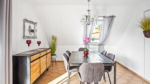 A modern dining area with a wooden cabinet, a chandelier, and a dining table with chairs.