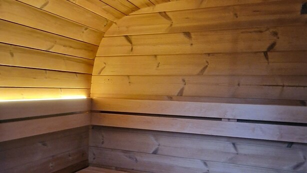 A wooden sauna with benches and a sloped ceiling. - The Railway Inn MK | Sauna & Jacuzzi | Family & Pet-Friendly | Sleeps upto 8 (Milton Keynes)