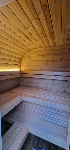 Puisesta laudelavasta ja kaltevasta katosta koostuva sauna.