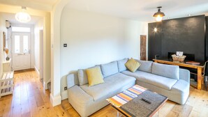 A modern living room with a grey sectional sofa, a wooden coffee table, and a black fireplace. - The Railway Inn MK | Sauna & Jacuzzi | Family & Pet-Friendly | Sleeps upto 8 (Milton Keynes)