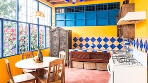 A kitchen with a wooden table, chairs, a stove, and a bench. - Villa La Trinidad (San José)