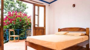 A single bed with a wooden frame and a beige mattress in a room with a tiled floor and a wooden door. - Villa La Trinidad (San José)