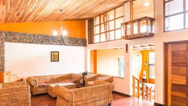 A lobby with wicker furniture, a stone accent wall, and a wooden ceiling. - Villa La Trinidad (San José)