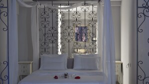 Ein Schlafzimmer mit Himmelsbett, weißer Bettwäsche und einem kleinen Nachttisch mit Lampe.
