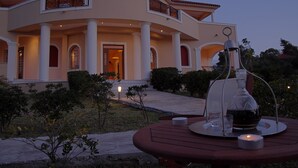 Ein großes, elegantes Gebäude mit einer geschwungenen Fassade, mehreren Säulen und einem gepflegten Garten.