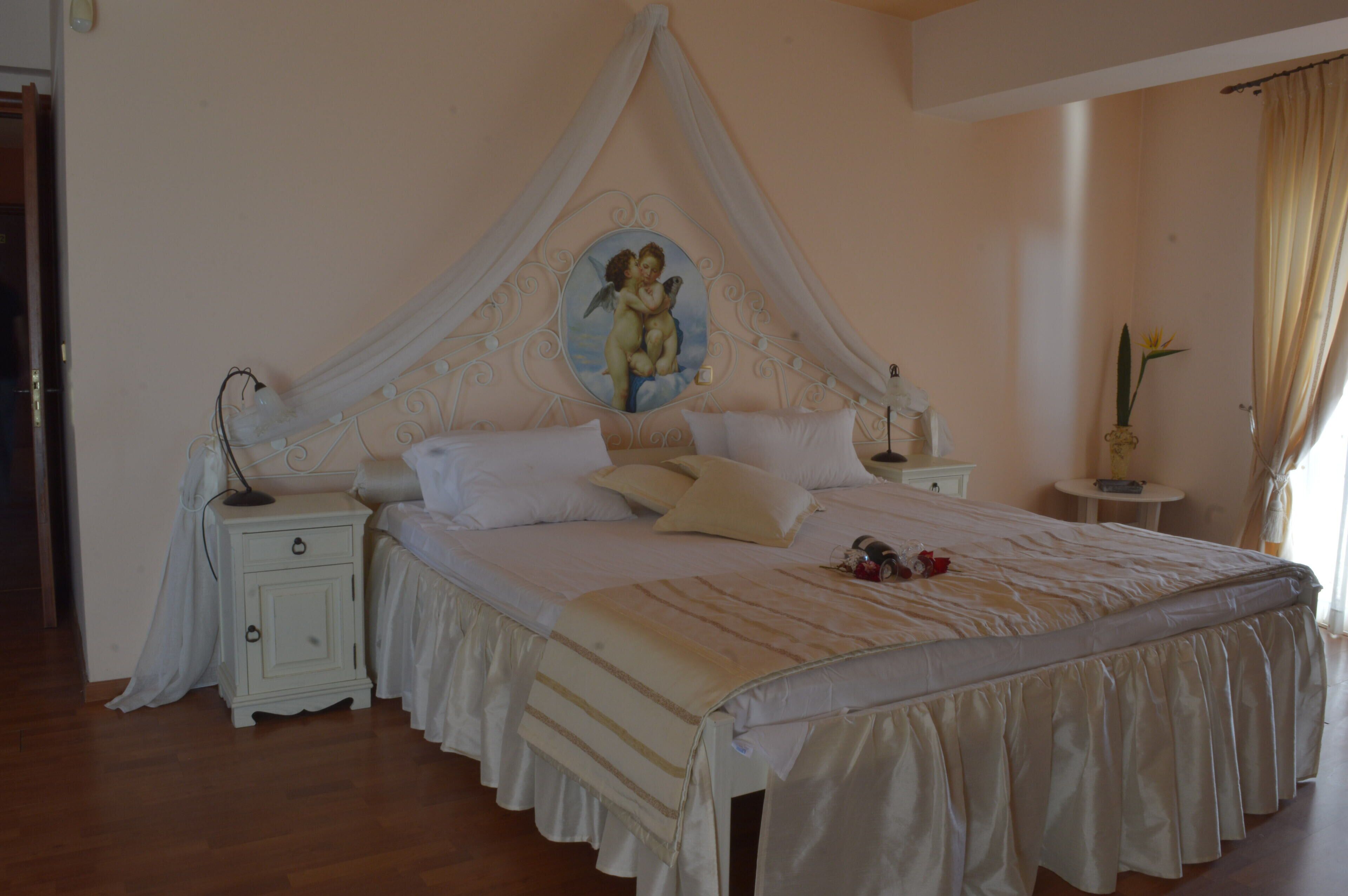 Ein Schlafzimmer mit Baldachinbett, Nachttisch, kleiner Rundtisch und einer Topfpflanze.