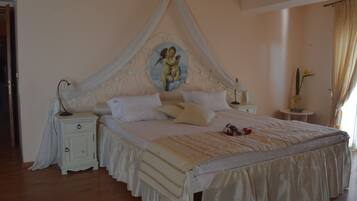 Ein Schlafzimmer mit Baldachinbett, Nachttisch, kleiner Rundtisch und einer Topfpflanze.