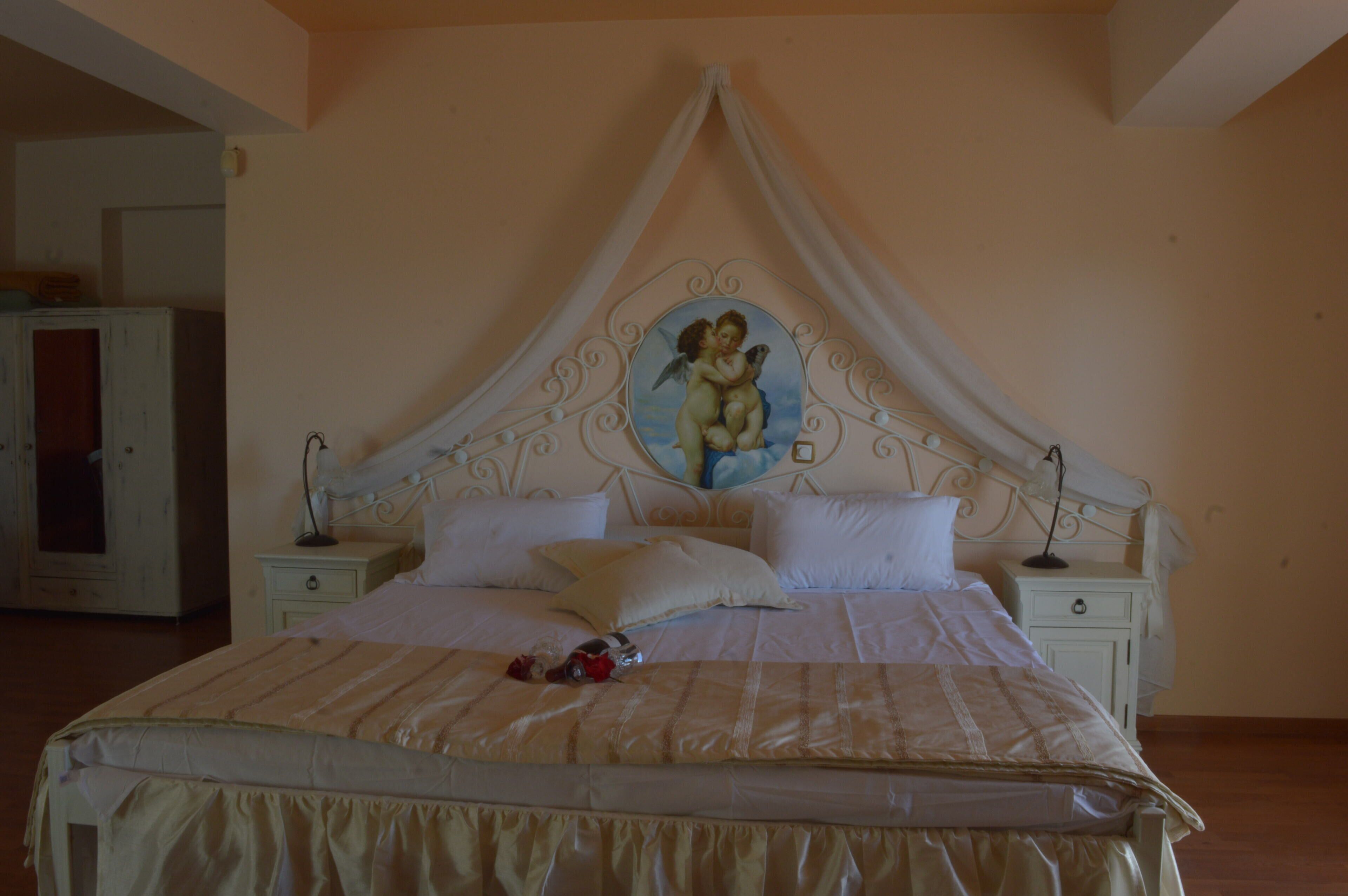 A bedroom with a canopy bed, a nightstand with a lamp, and a wall-mounted picture.