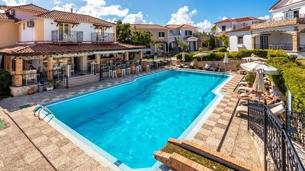 Ein Swimmingpool, umgeben von einer Terrassenanlage mit Außenmöbeln und einer Bar.