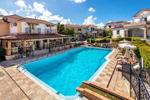 A swimming pool surrounded by a patio area with outdoor seating and a bar. - Anagenessis Suites & Spa Resort - Adults Only (Zakynthos)
