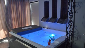 Ein moderner Wellnessraum mit einer Whirlwanne, einem kleinen Tisch und einer Wand mit einem Gittermuster.