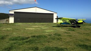 Un hangar con un piccolo aeromobile parcheggiato all'esterno.