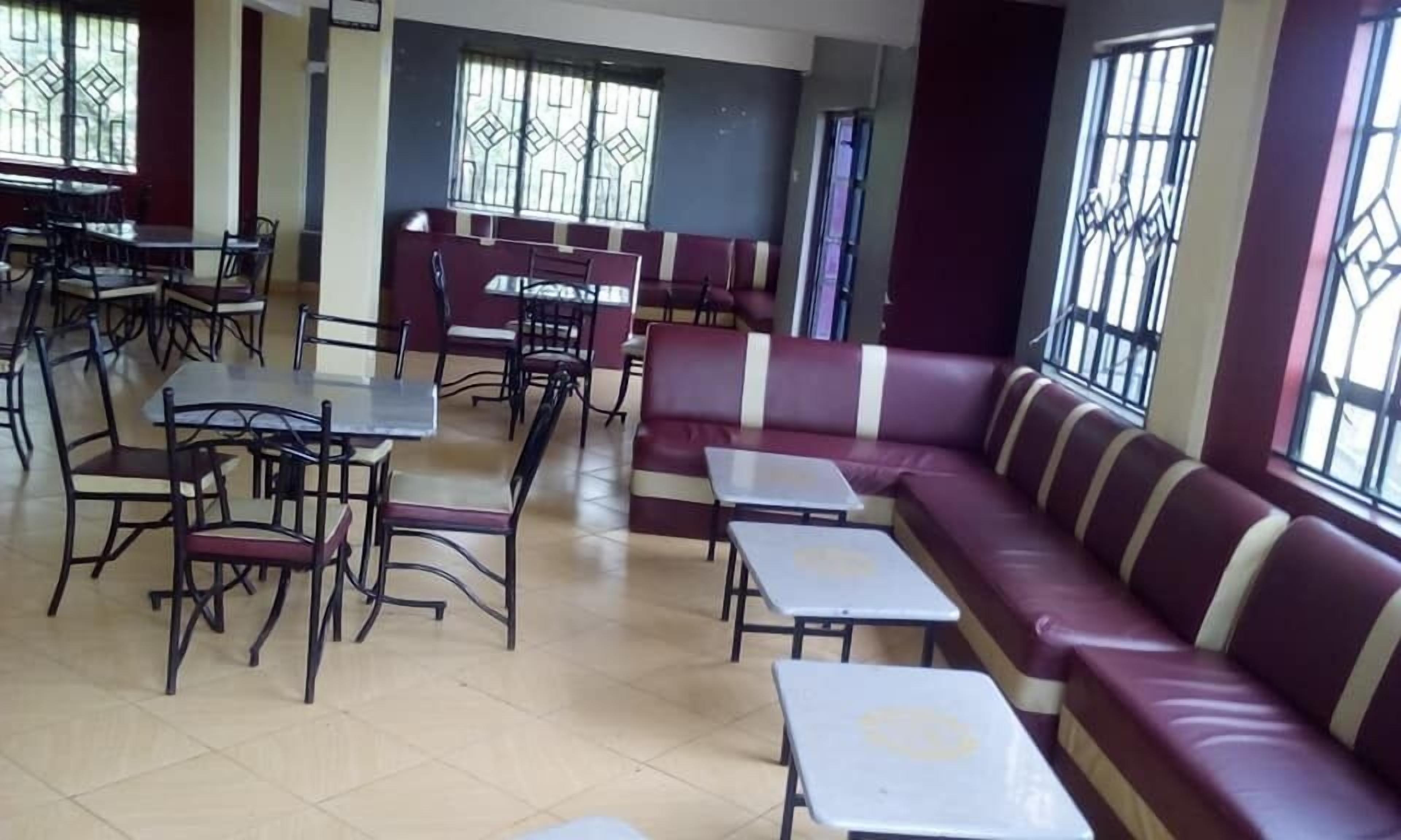 A dining area with tables and benches, large windows with bars, and a tiled floor.