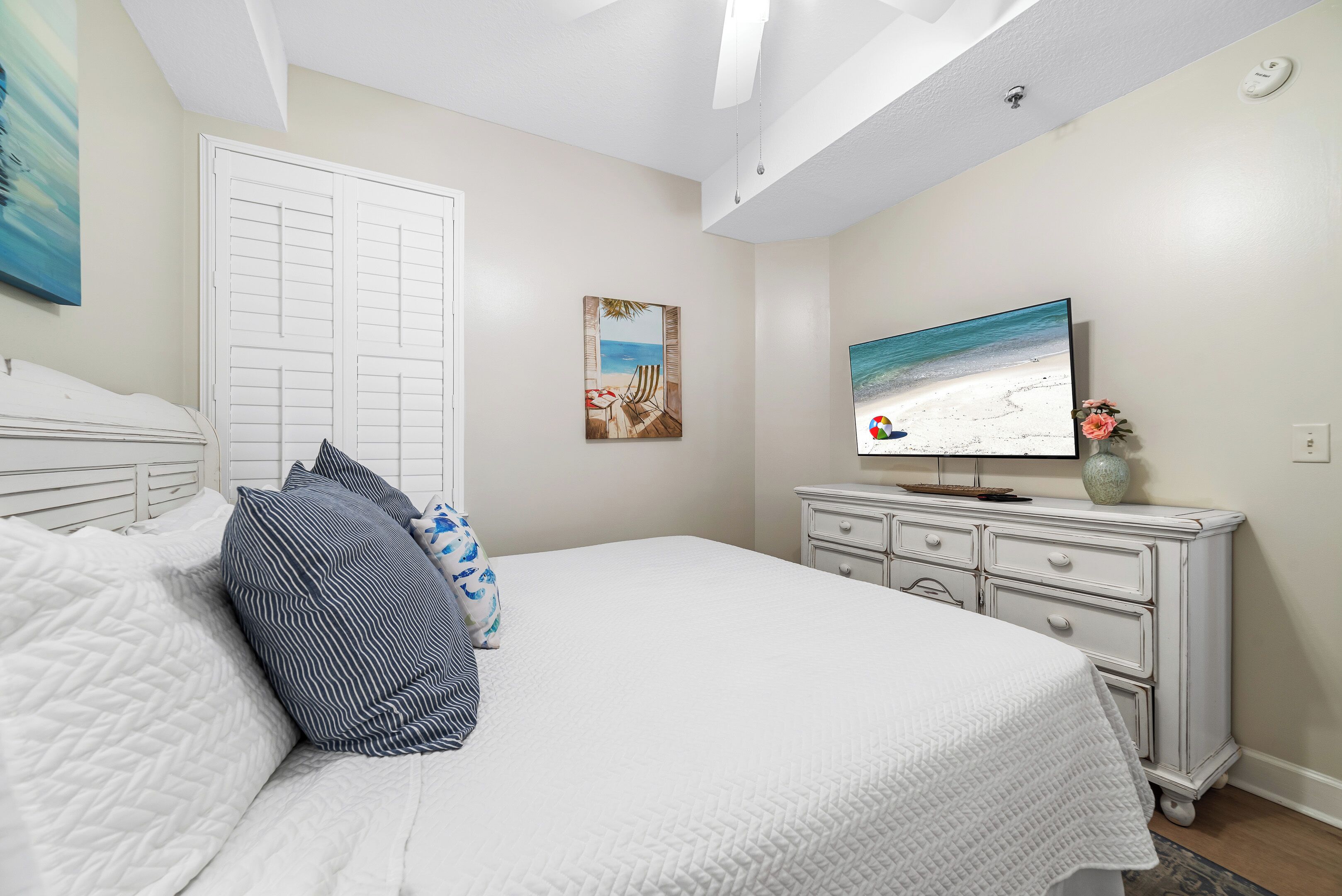 A bedroom with a bed, a TV, a dresser, and a door.