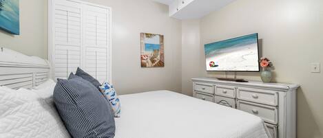 A bedroom with a bed, a TV, a dresser, and a door.