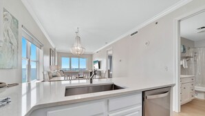 Een moderne keuken met een groot eiland, witte kasten en een inbouw vaatwasser.