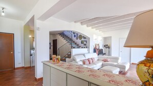 A spacious living room with a white sofa, a coffee table, and a staircase leading to an upper floor. - Luxurious home in Partinico (PA) (Partinico (PA))