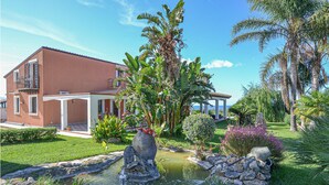 A house with a patio, a small pond, and tropical plants. - Luxurious home in Partinico (PA) (Partinico (PA))