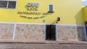 The exterior of OYO Hotel, featuring a yellow facade, a prominent entrance with a black door, and a sign above the door. - Capital O Hotel Emperadores Inn, Atlixco (Atlixco)