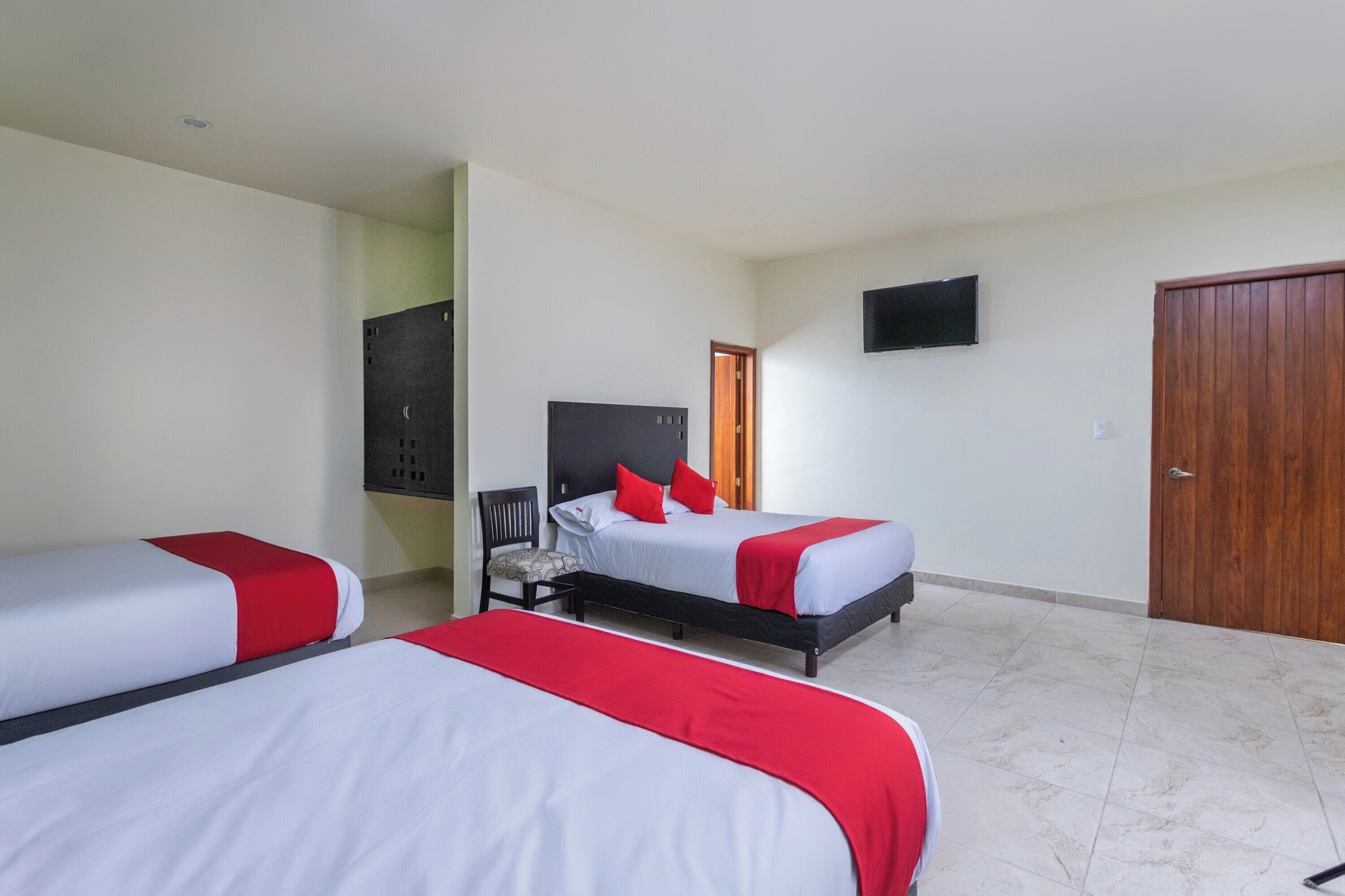 Una habitación de hotel con dos camas, televisión y un armario.