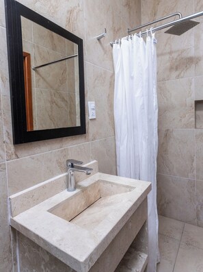 A bathroom with a marble sink, a mirror, a shower, and a towel rack. - Capital O Hotel Emperadores Inn, Atlixco (Atlixco)