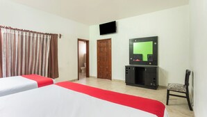 Ein Hotelzimmer mit zwei Betten, einem Fernseher, einem Schreibtisch und einem Stuhl.