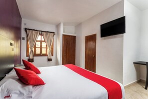 A hotel room with a bed, a TV mounted on the wall, and a window with curtains. - Capital O Hotel Emperadores Inn, Atlixco (Atlixco)