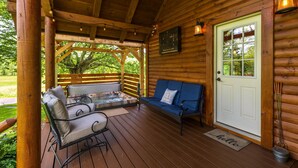 Una terraza de madera con un jacuzzi, zona de estar y una puerta con ventana.