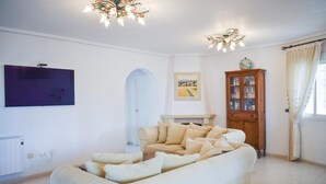 Ein Wohnzimmer mit einem beigefarbenen Sofa, einem Holzschrank, einem Kamin und einem Bild an der Wand.
