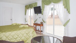 Ein Zimmer mit einem Bett, einem Fernseher, einem kleinen Tisch und einem Sessel.