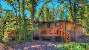 A log cabin with a wooden deck and a staircase leading to the entrance. - Creekside Retreat - Charming Cabin w/Deck, A/C, Firepit, & Billy Creek View (Pinetop-Lakeside)