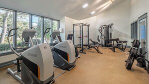 Una palestra con macchinari cardio, attrezzature per sollevamento pesi e un'ampia finestra che offre luce naturale.