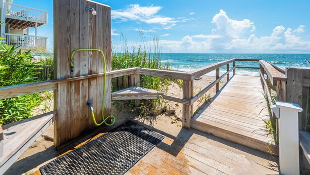 Un molo di legno che conduce a una spiaggia, con una struttura in legno sulla sinistra.