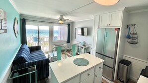 A compact kitchen with a central island, a dining area with a view, and a balcony with a view.