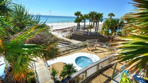 A pool area with a hot tub, surrounded by palm trees and a beach view.