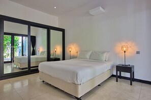 A modern bedroom with a large bed, two bedside tables with lamps, and a large mirror. - Villa Arus (Seminyak)