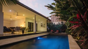 A swimming pool with a view of a dining area and a mural. - Villa Arus (Seminyak)
