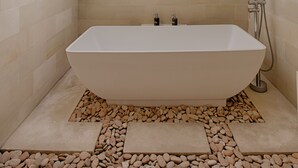 A modern bathroom with a freestanding bathtub, a skylight, and a decorative tile wall. - Villa Arus (Seminyak)