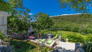 A patio with stone walls, a grill, and outdoor seating. - Amazing home in Klenovica (Klenovica)