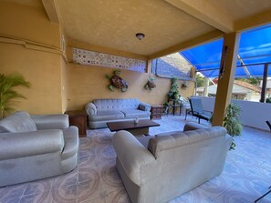 Un espace extérieur aménagé, abrité et doté d’un canapé, de fauteuils et d’une table basse.