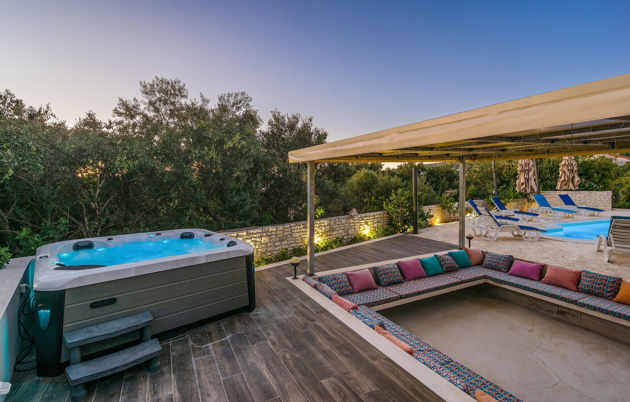 A hot tub, lounge chairs, and a covered seating area on a wooden deck.