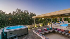 Un jacuzzi, sillas de descanso y una zona de estar techada en una terraza de madera.