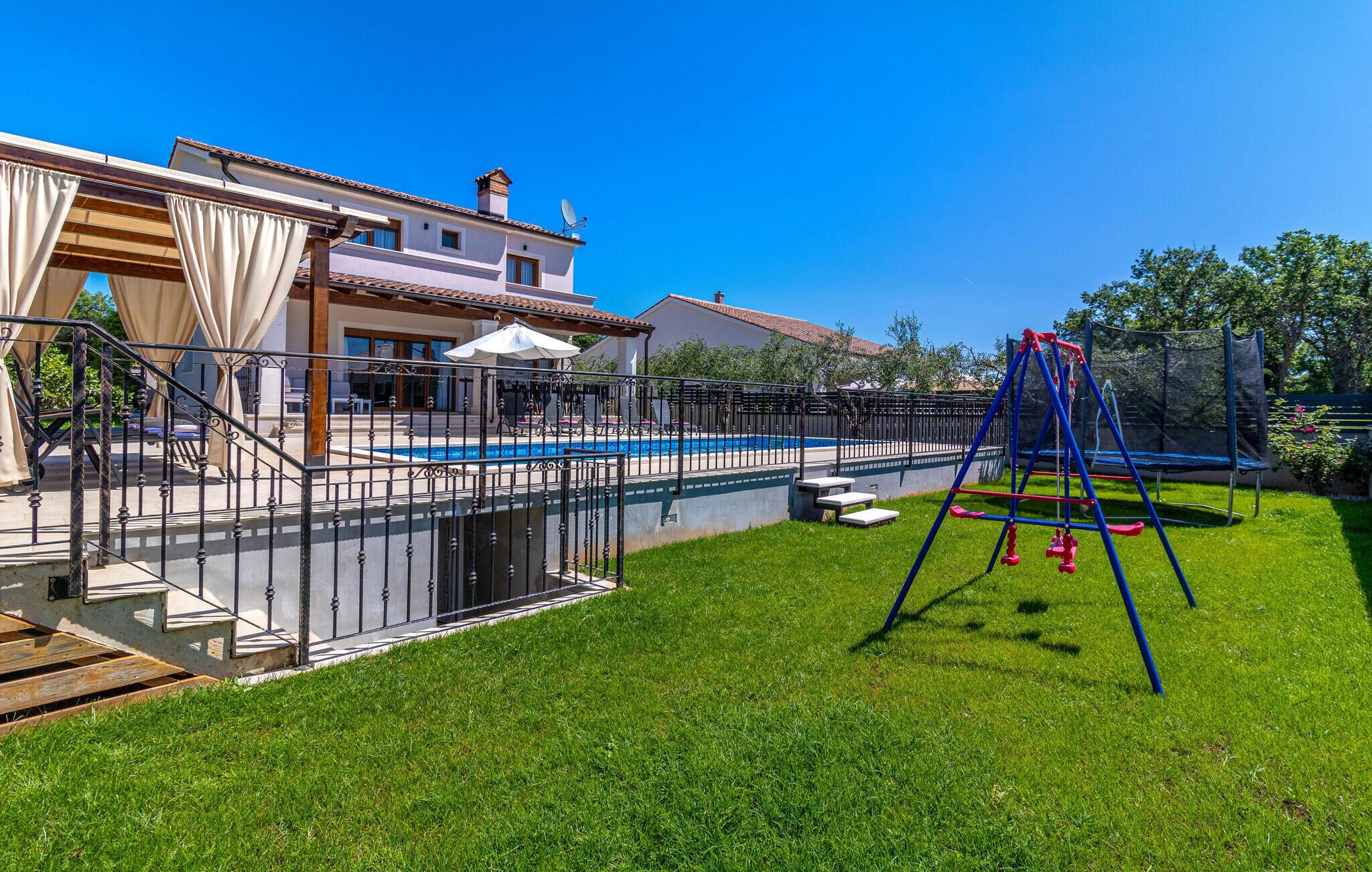 A residential property with a swimming pool, a fenced patio area, and a swing set.