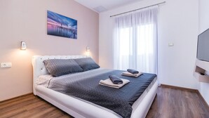 A modern bedroom with a bed, a painting, a TV, and a window with curtains. - Pet friendly home in Vodnjan (Vodnjan)