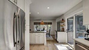 A modern kitchen with white cabinetry, a central island, and a dining area with a view.