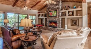 A spacious living room with leather sofas, a fireplace, and a stone accent wall.