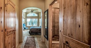 A hallway with wooden doors, a rug, and a bed in the background.