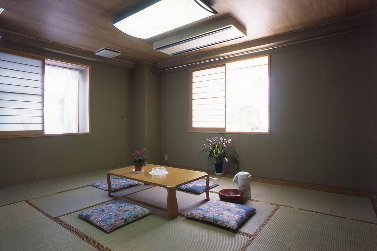 Une pièce de style japonais traditionnel, avec un sol recouvert de tatamis, une petite table en bois et des paravents en papier de riz (shoji).